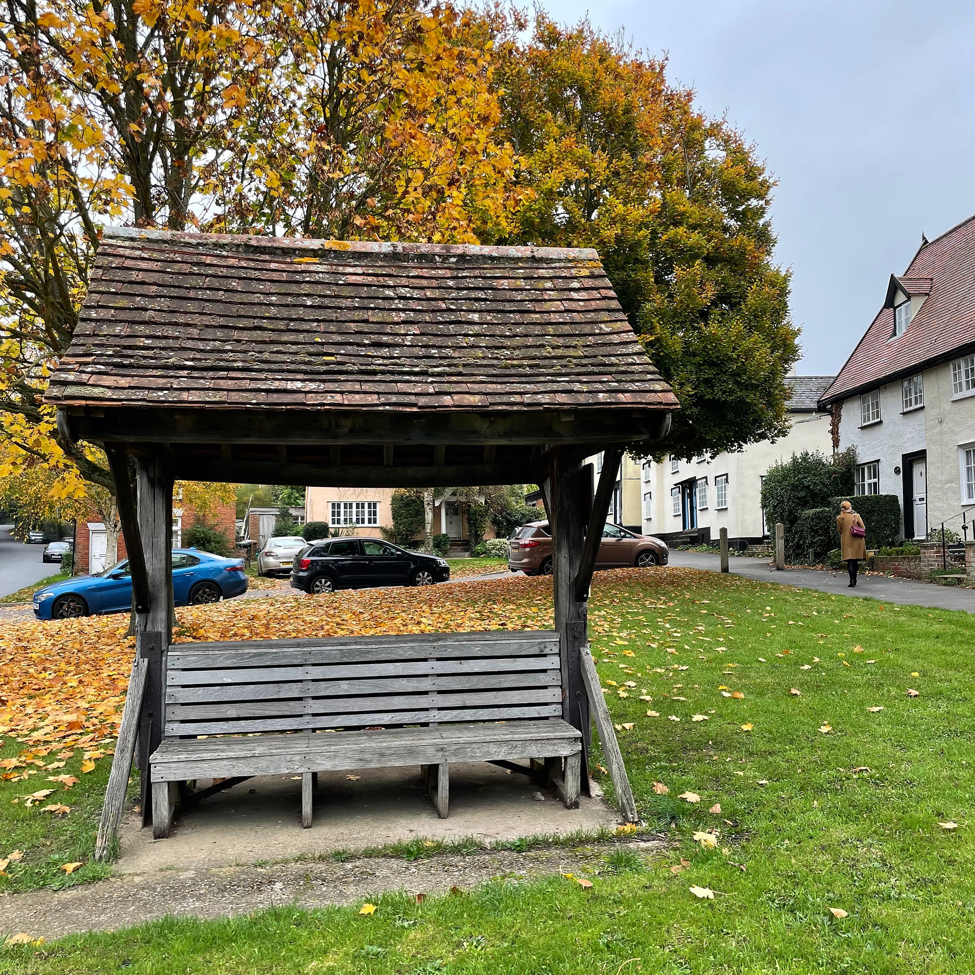 A covered well seat in front of an autumnal tree