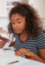 Teenage girl studying for exams in kitchen with notes on table