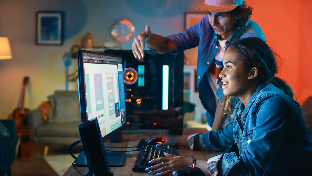 Teenage boy and girl work on digital media assignment on computer