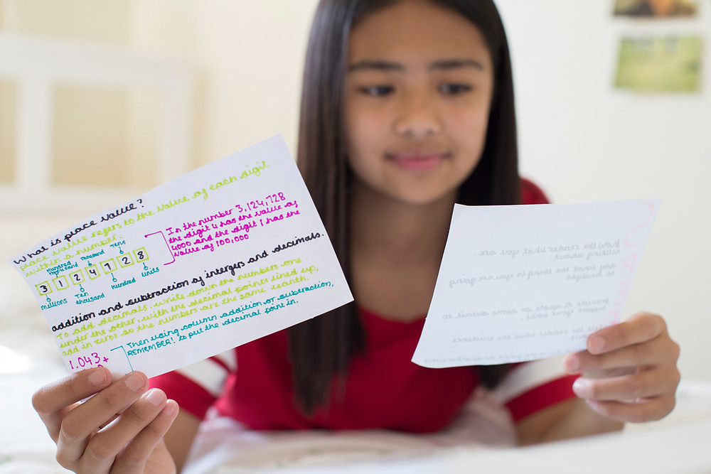 Teenage girl on bed using flash cards to help her revise for her upcoming exams