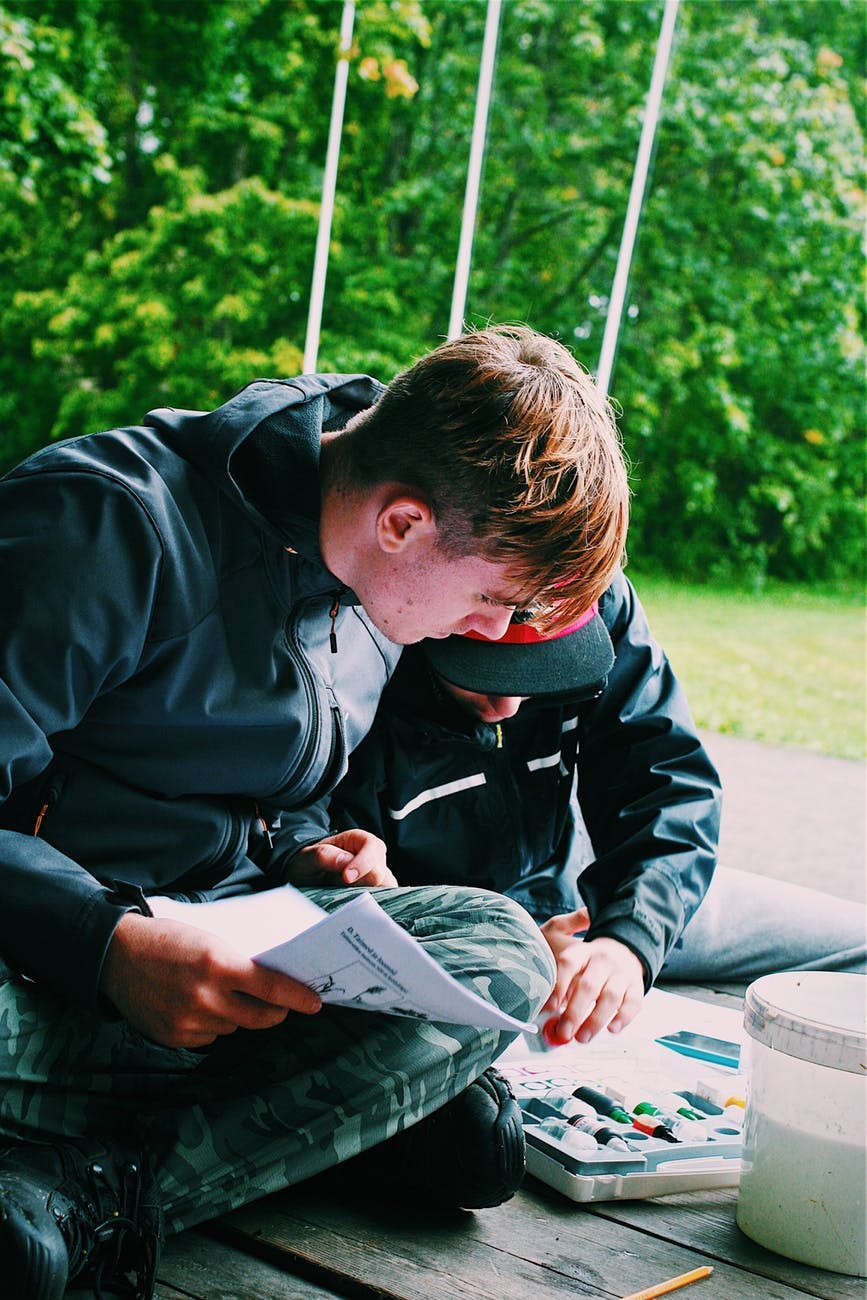 Two teenage boys outside looking at map and studying together