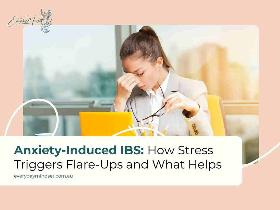 Woman in office holding glasses, appearing stressed. Laptop and coffee nearby. Text: Anxiety-Induced IBS: How Stress Triggers Flare-Ups.
