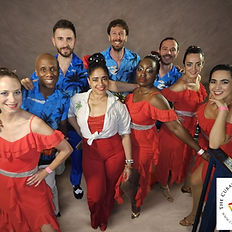 Group of dancers in red and blue outfits pose with the logo for The Cuban School of Arts