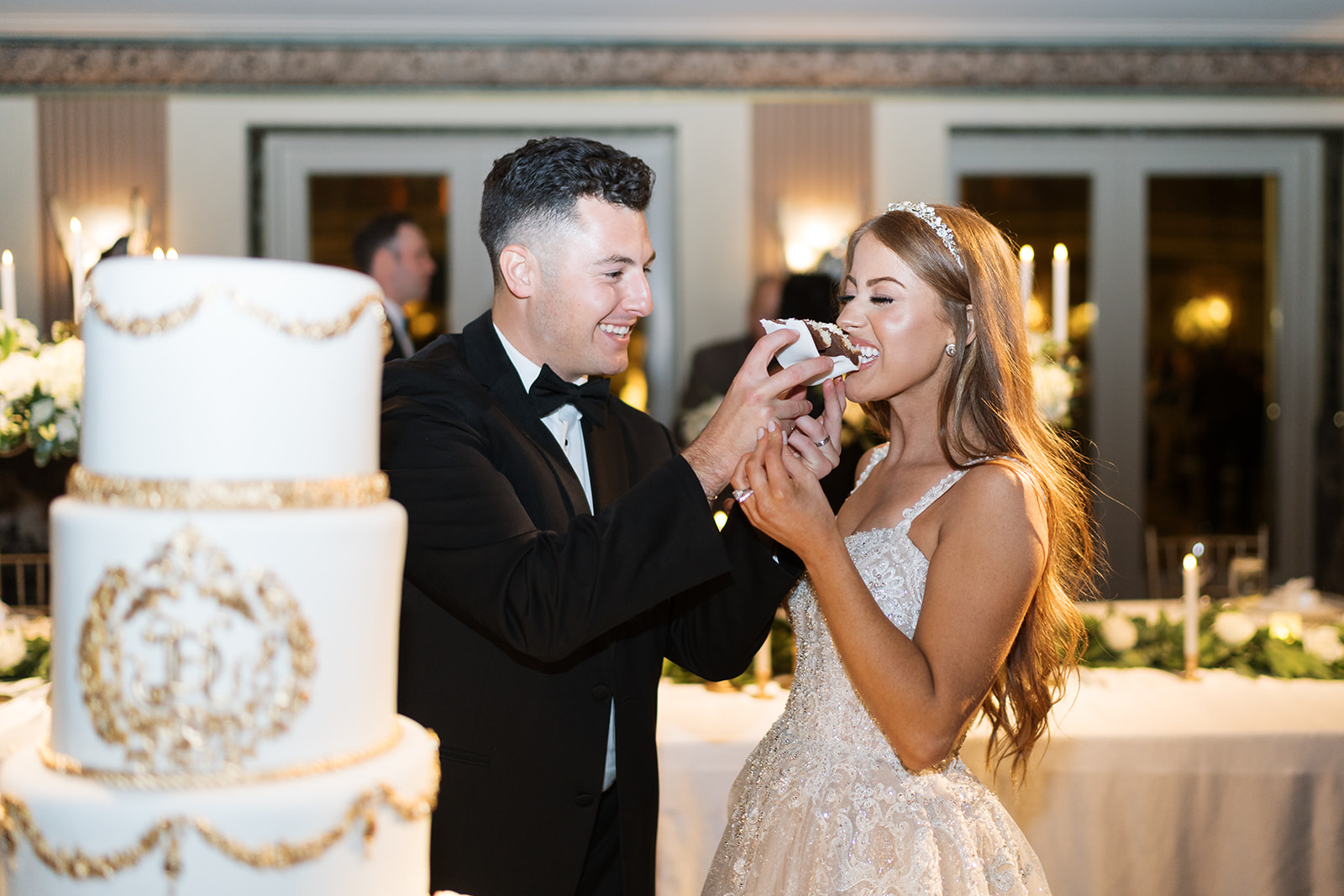 Dom and Hayley laughing together while cutting and sharing their wedding cake