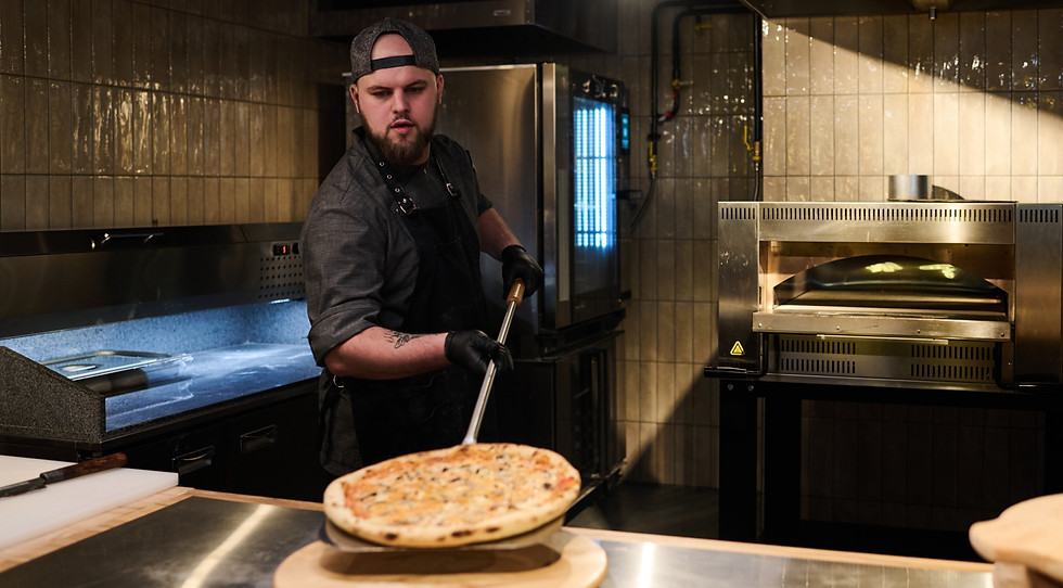 young-chef-putting-hot-baked-pizza-round-wooden-board.jpg