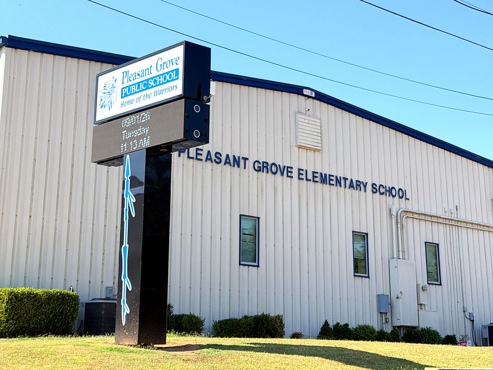 Pleasant Grove Elementary School building with sign reading Pleasant Grove Public School, Home of the Warriors, under a clear blue sky