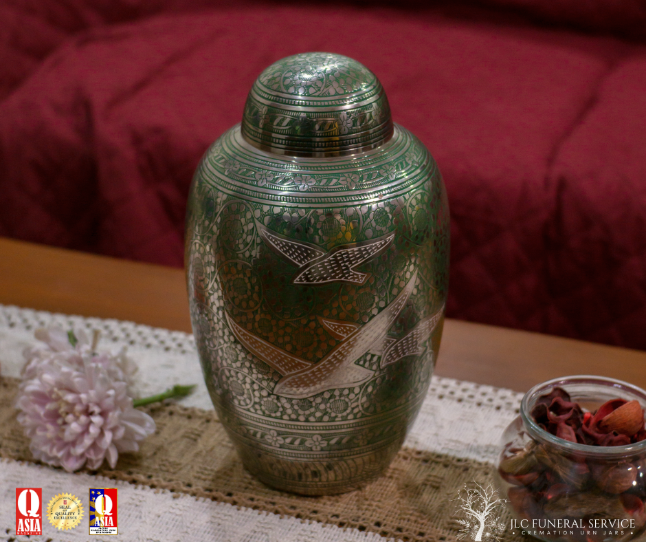 Stainless brass cremation urn with carved dove detailing.