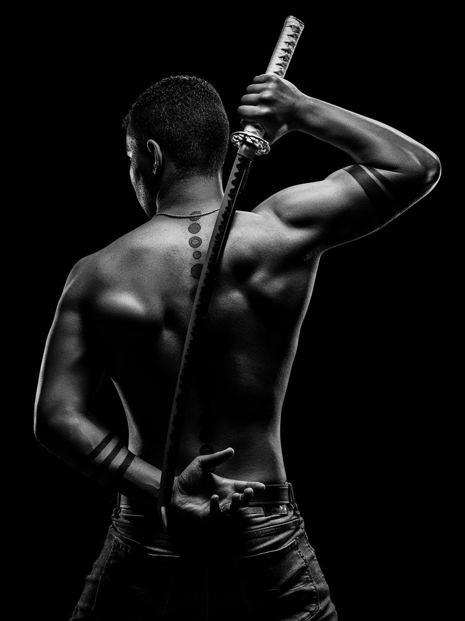 Creative portrait of man with his back to camera. Man is holding a samurai sword.