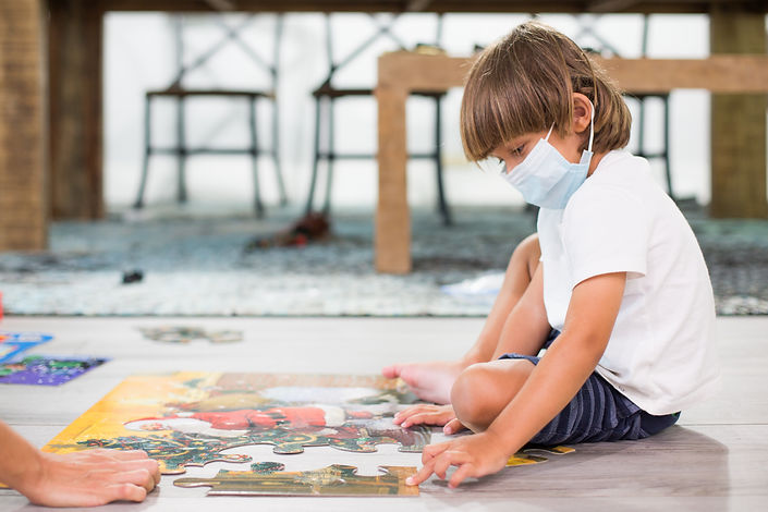 Child with a mask doing puzzle