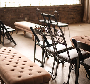 Iron chairs and elegant benches arranged at our Crossroads, Kansas City wedding venue, showcasing a rustic farmhouse ceremony setup.