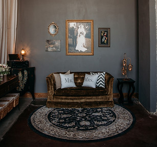 Private suite bridal lounge at the Crossroads, Kansas City venue featuring a couch, elegant round rug, and art wall, included in all-inclusive wedding packages.