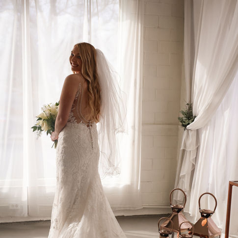 Bride standing near a large window with sheer curtains at our Liberty, Missouri wedding venue, showcasing an affordable and stress free all-inclusive wedding setup.