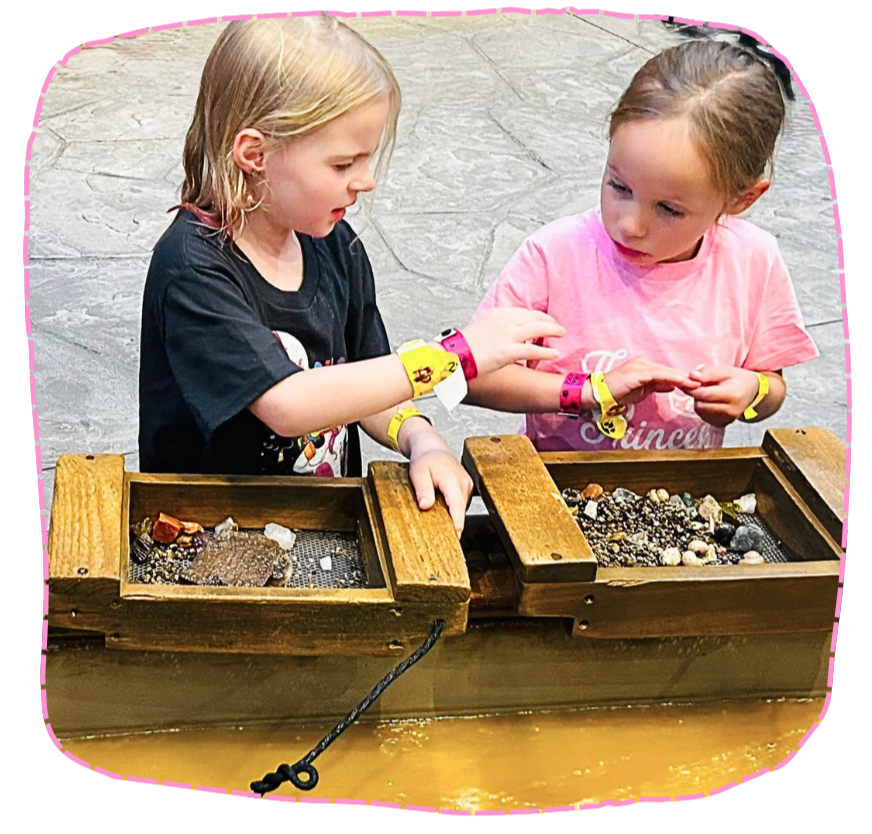 2 kids talking in front of the wooden box