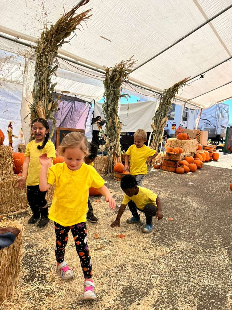 kids wearing yellow shirt on a pumpkin barn