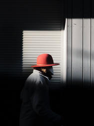 Street Fotografie von Guido Klumpe. frau mit rotem hut im Lichtspot