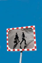 Ein Sicherheitsspiegel auf der Straße zeigt einen Mann in der Luft.