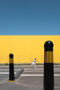 Street Fotografie von Guido Klumpe. Junge rennt vor gelber wand