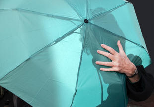 Eine frau will ihren Regenschirm auf keinen Fall hergeben.