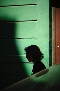 Silhouette einer Frau vor grüner Wand mit Spiegelung