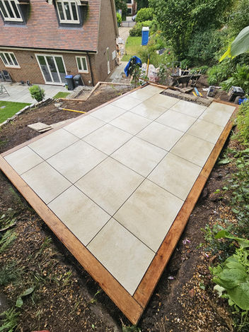 a patio with cream porcelain tiles and a sleeper edging
