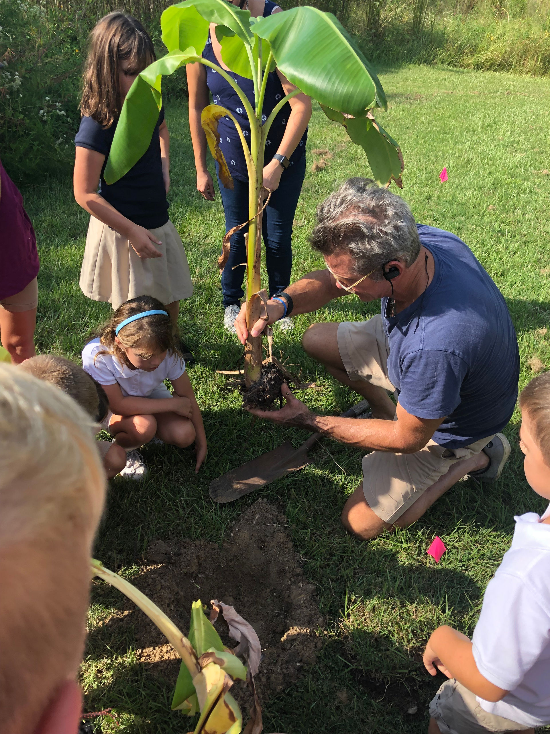 Teaching local school kids about planting banana plants