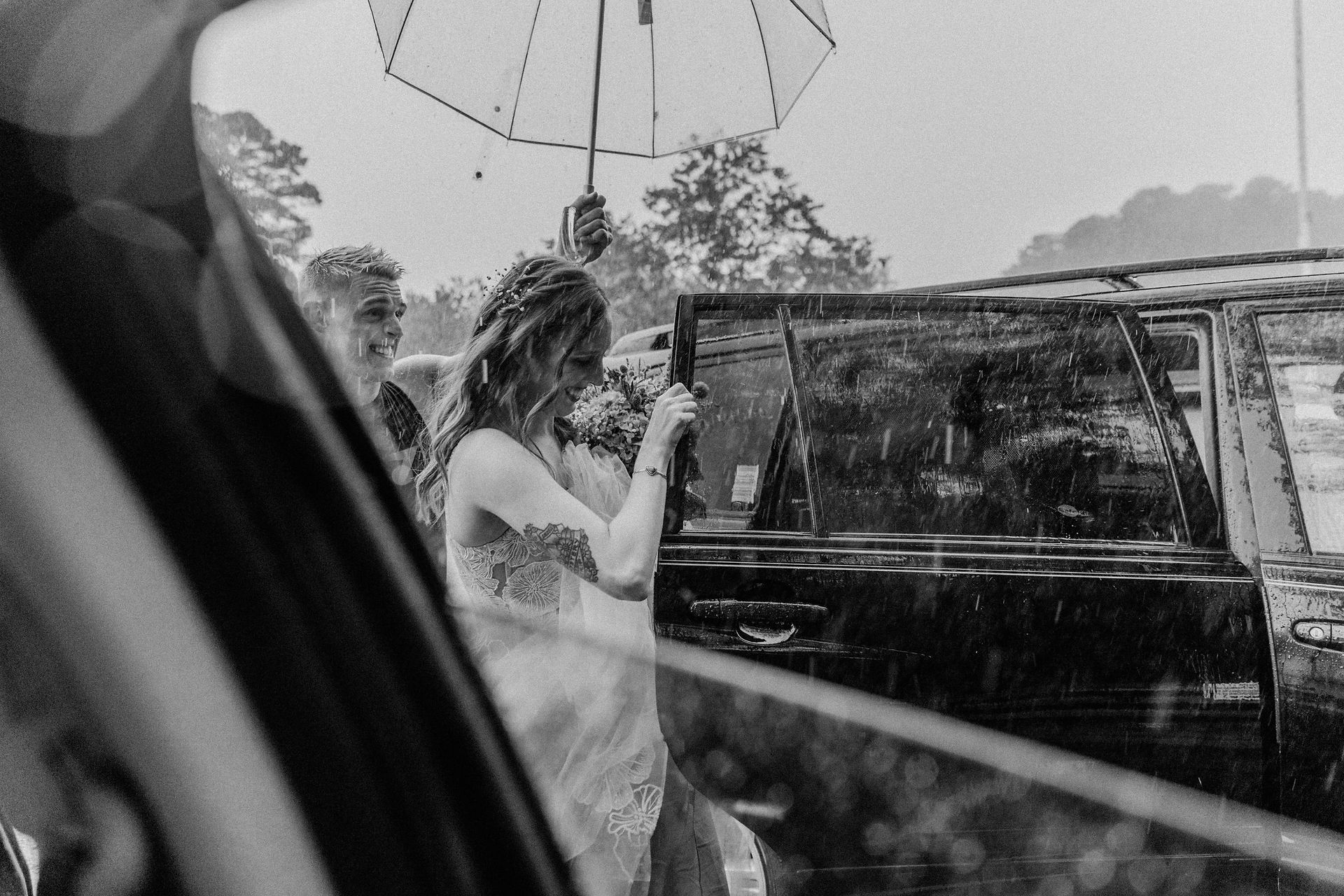 Liz exits a car while her brother holds an umbrella over her