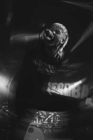 A black and whit live photo of a singer in Raiders UK with a radial blur, and the singer leaning forward and singing into the microphone, playing in Cardiff