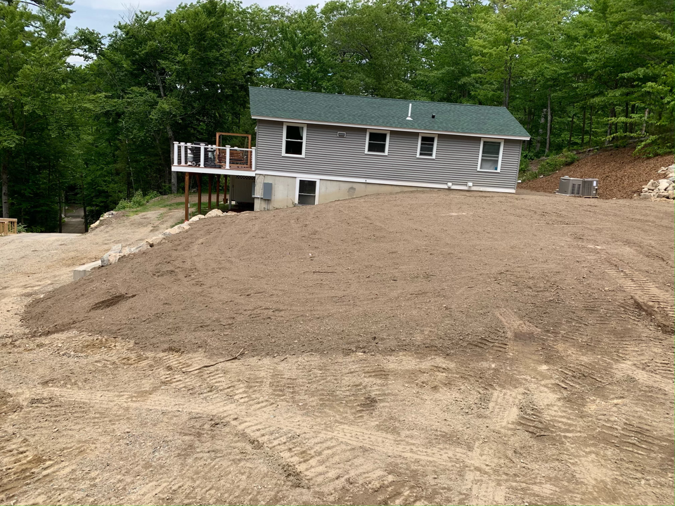 Home with driveway graded by excavator