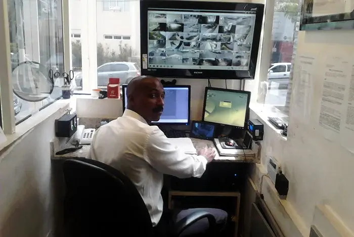 foto de uma portaria com o porteiro interagindo com um monitor de controle de acesso