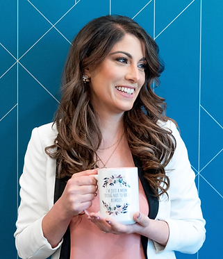 portrait of Dr. Michelle with a blue background where she is smiling holding a coffee mug