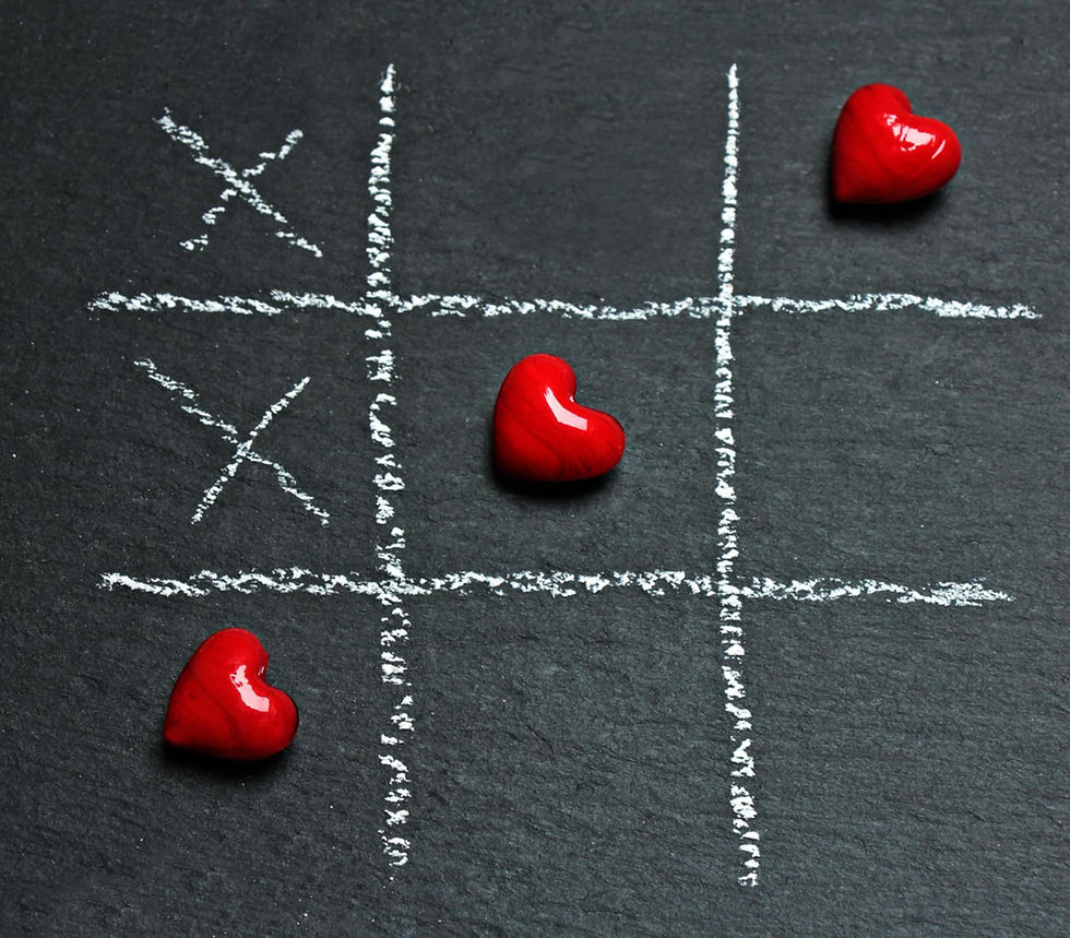 Tic-tac-toe game on chalkboard with red heart pieces and X marks. Two hearts are placed, adding a playful, romantic mood.