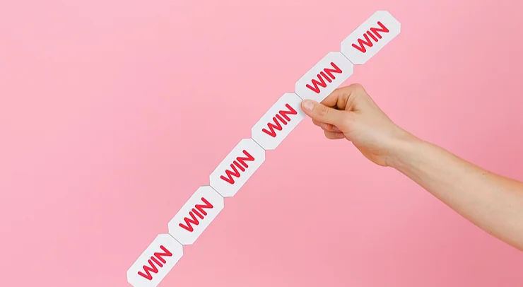Hand holding a strip of tickets with "WIN" text, against a pink background. The mood is uplifting and playful.