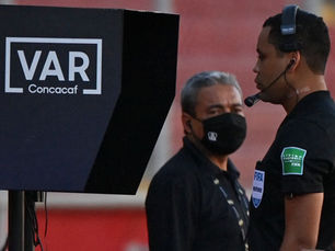 A football referee consults a pitch-side monitor during a match, using video technology to review a crucial decision.