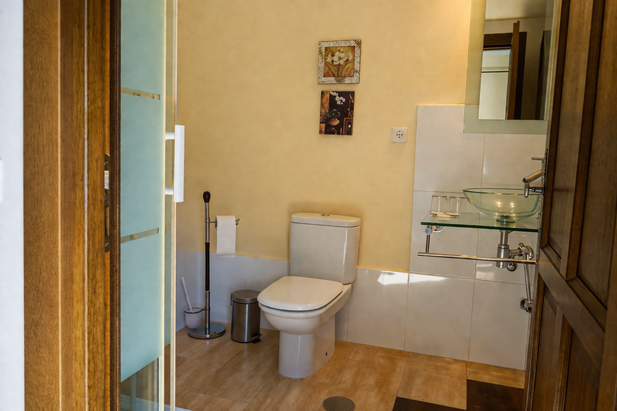 Baño con inodoro y lavabo de cristal transparente.