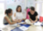 Three people on the sample team standing around a table looking at documents