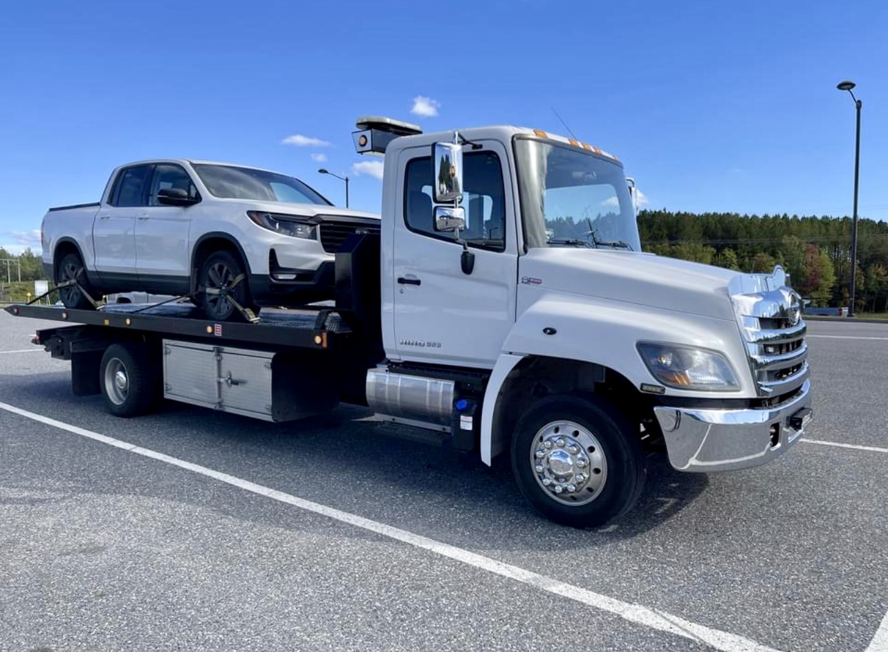 Dépanneuse à plateau transportant une camionnette
