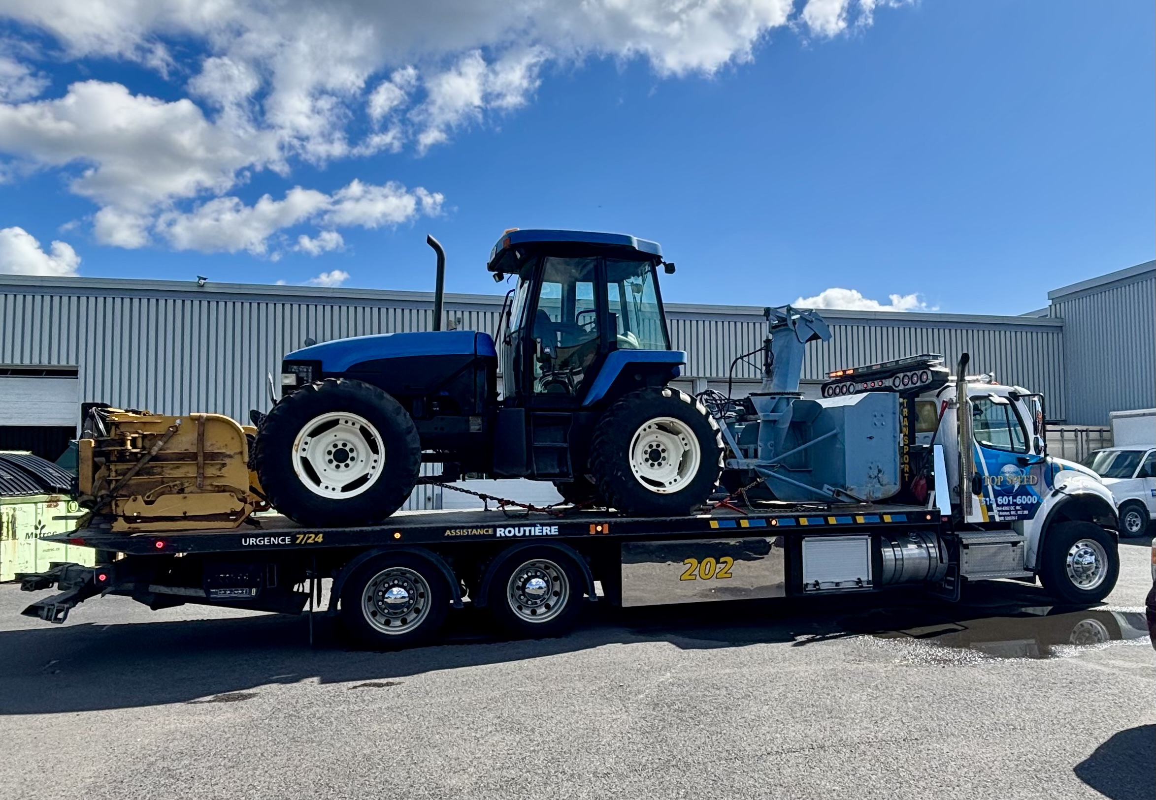 Transport d’un tracteur bleu sur une plateforme