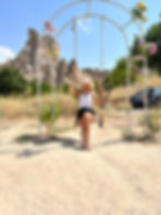A women sitting on a swing with a beautiful background in cappadocia, turkey.