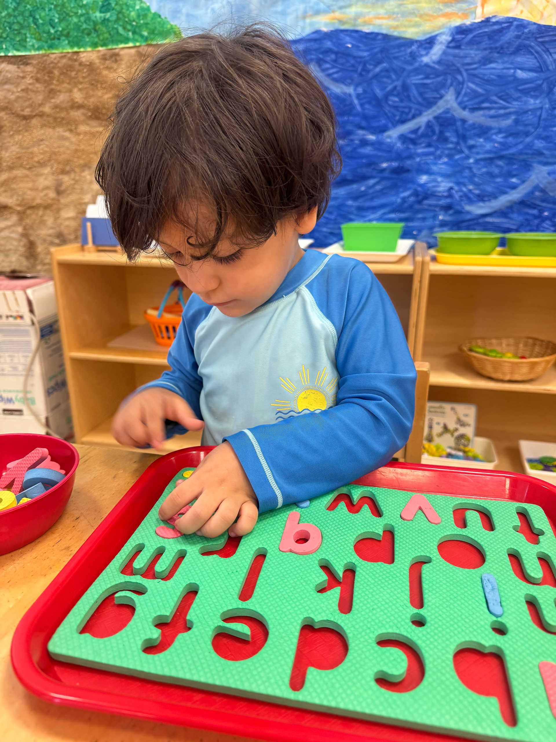 A toddler practices their letters at Hudson Montessori School's Jersey City summer camp.