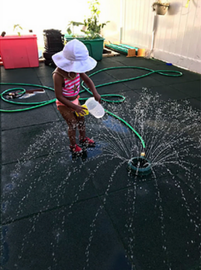 Hudson Montessori primary student plays with splash pad outside during a camp activity. 