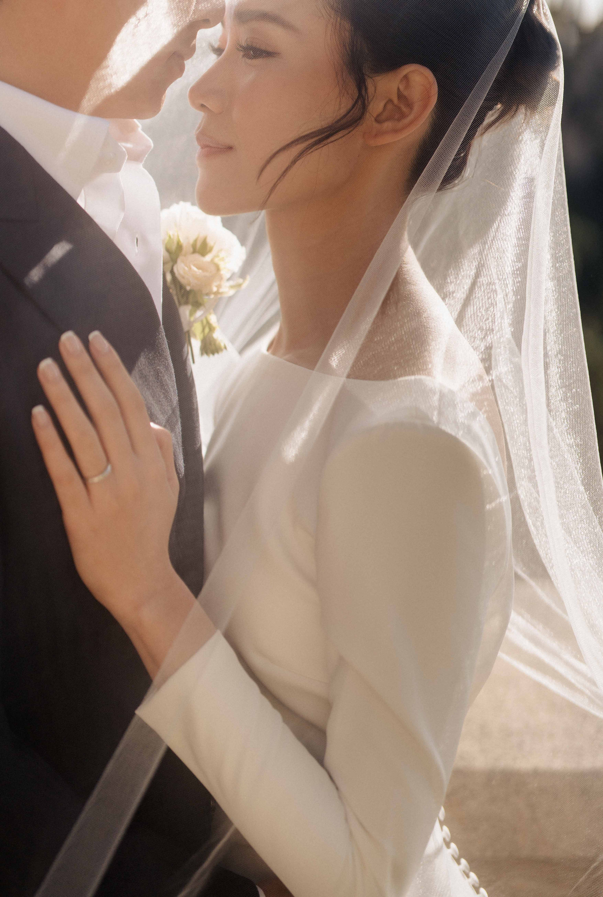 Closeup of the bride hugging her husband under her veil