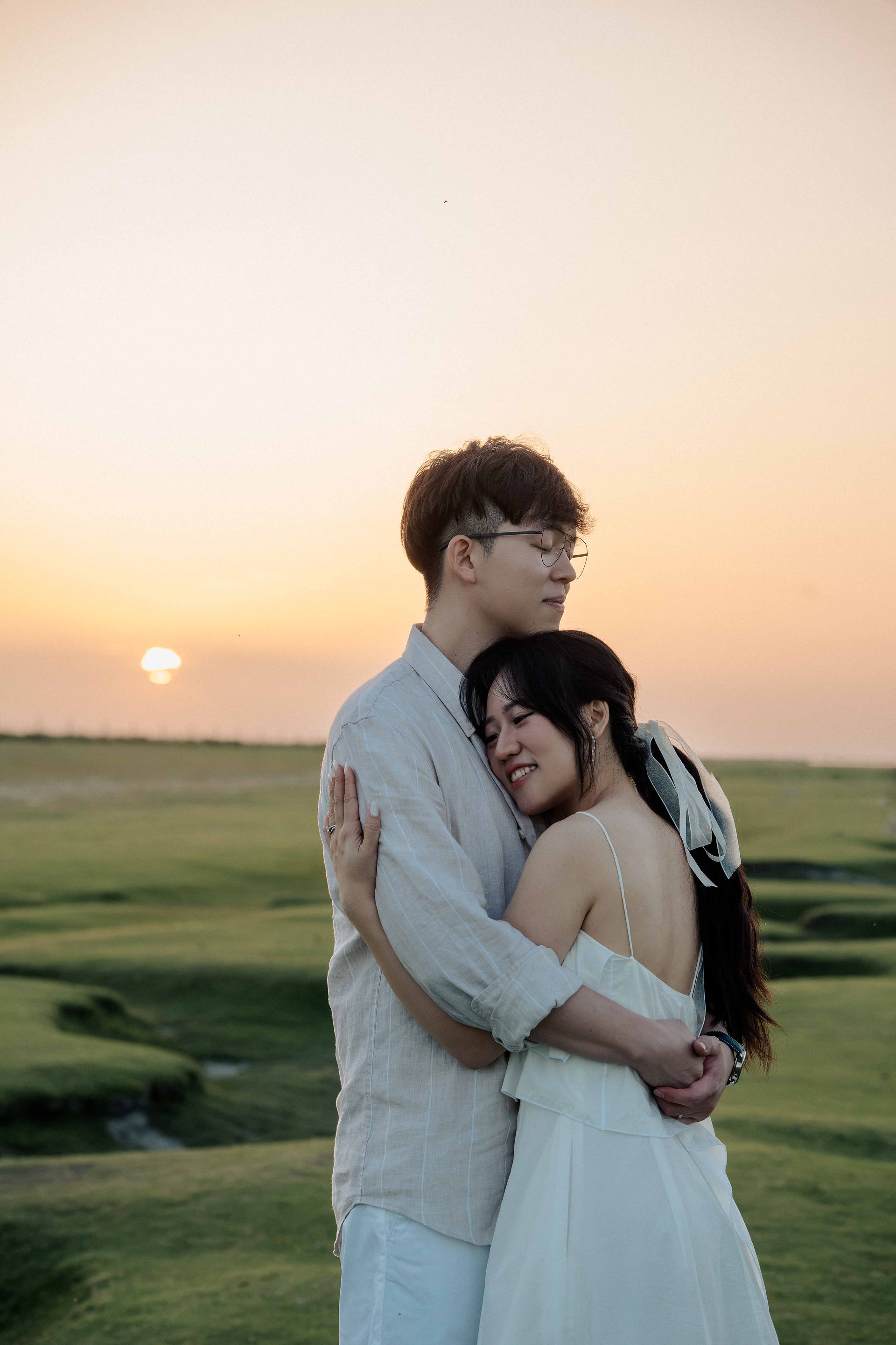 Close-up portrait of a couple in love hugging tightly during a romantic sunset shoot in the Normandy salt meadows
