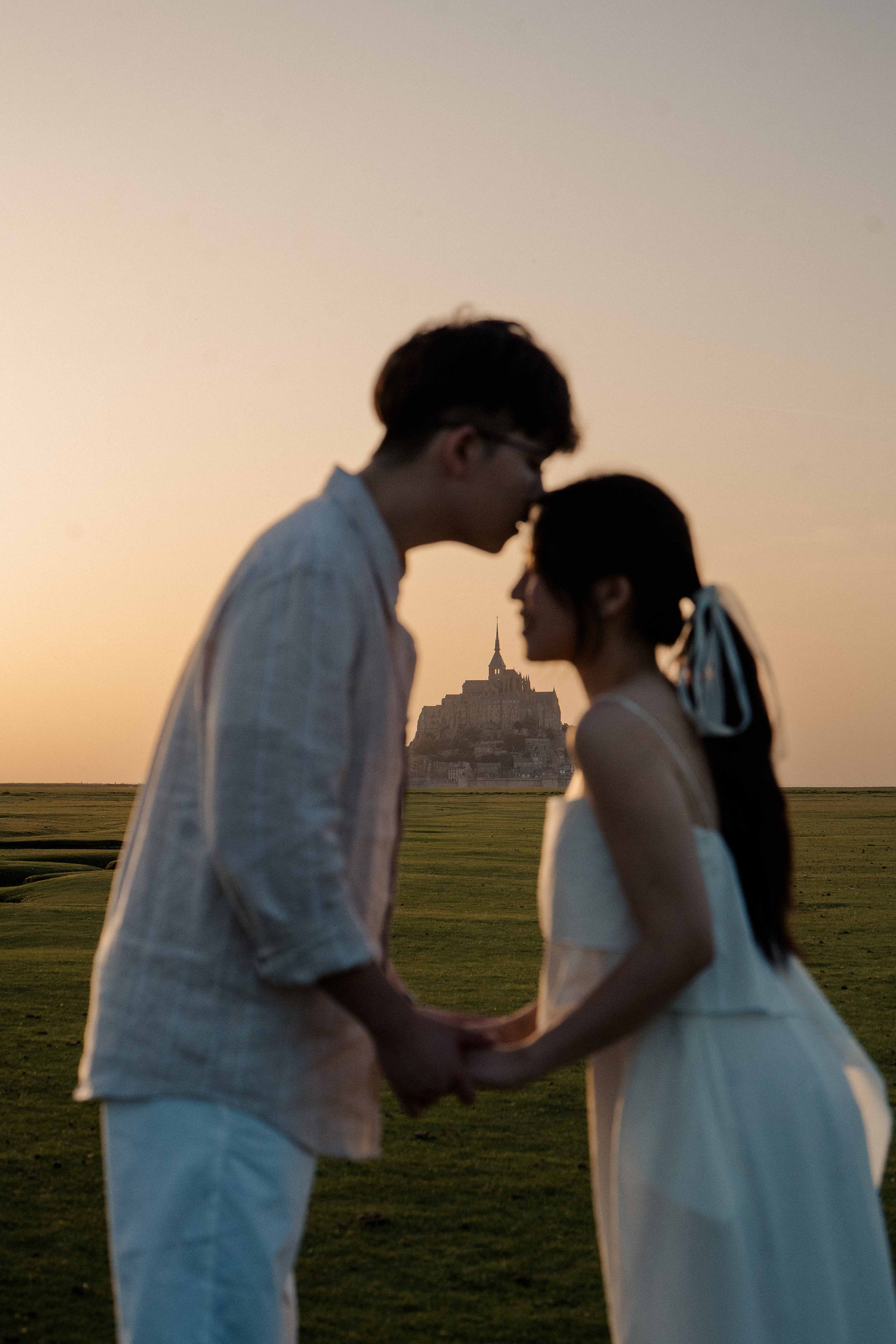 Romantic silhouette portrait of a couple kissing at sunset in front of Mont Saint-Michel