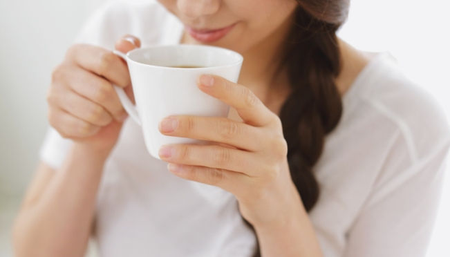 Woman holding a warm white mug, enjoying a cup of bone broth or collagen drink for hormonal health
