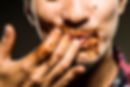 a man licking his fingers with sauce dripping