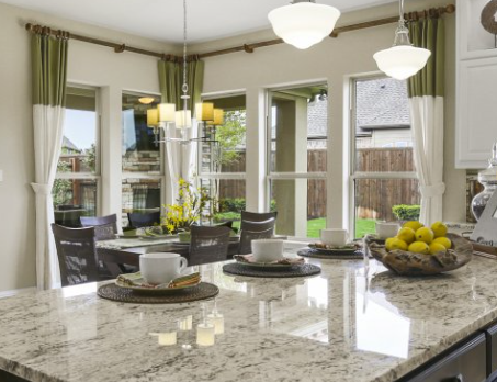 A white kitchen with brown accents, large windows, and marble countertops
