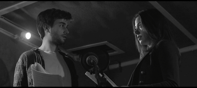 Scene from short film Wuthering Heights of man and woman staring at each other across a microphone in a recording studio
