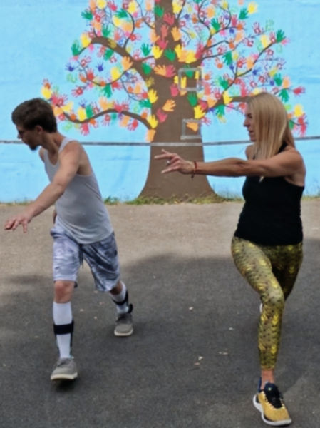 Two people in a lunge position with their arms extended and twisting at their core