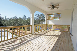 a porch with a wooden railing and a ceiling fan