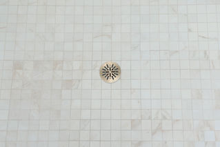 a white tiled floor with a drain in the middle